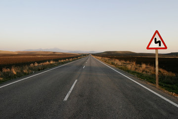 carretera recta con señal de curva peligrosa