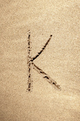 Alphabet letter K handwritten in sand