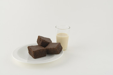 Three brownies with a glass of milk