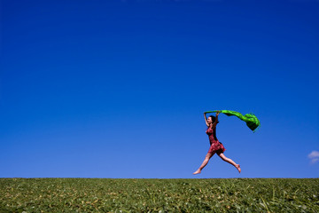 Woman running along a green hill, free in summer