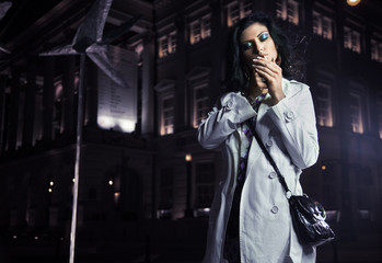 Beautiful brunette smoking in the city on the night