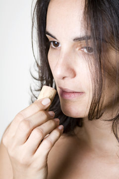 Pretty young woman sniffes on the cork of a wine bottle