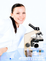 smiling brunette medical woman researching on a microscope