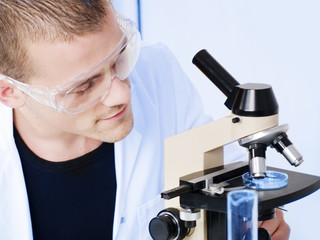 smiling man researching on a microscope