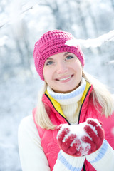 Smiling beautiful woman playing with snow.