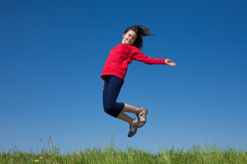 Girl jumping, running against blue sky
