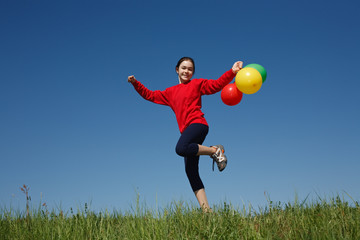 Girl holding balloons, running outdoor