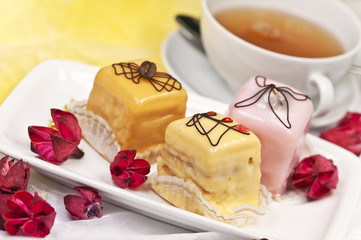 Petit Fours on a white plate with a cup of Tea