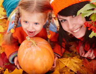 Happy family with child on autumn orange leaf, pumpkin.