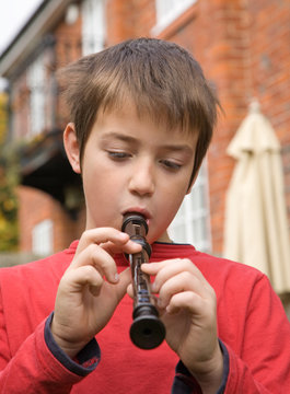 Young Boy Playing A Recorder Outside