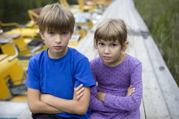 Fototapeta premium serious brother and sister sitting on piers