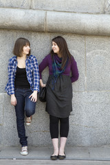 two teen girls talking at stone wall