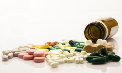 Medical bottle and colorful pills over white