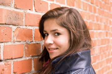 beautiful young girl lean on red brick wall