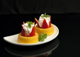 Two strawberry shortacakes on a white plate.