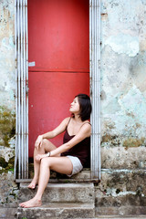 Fototapeta premium Girl sits in red doorway