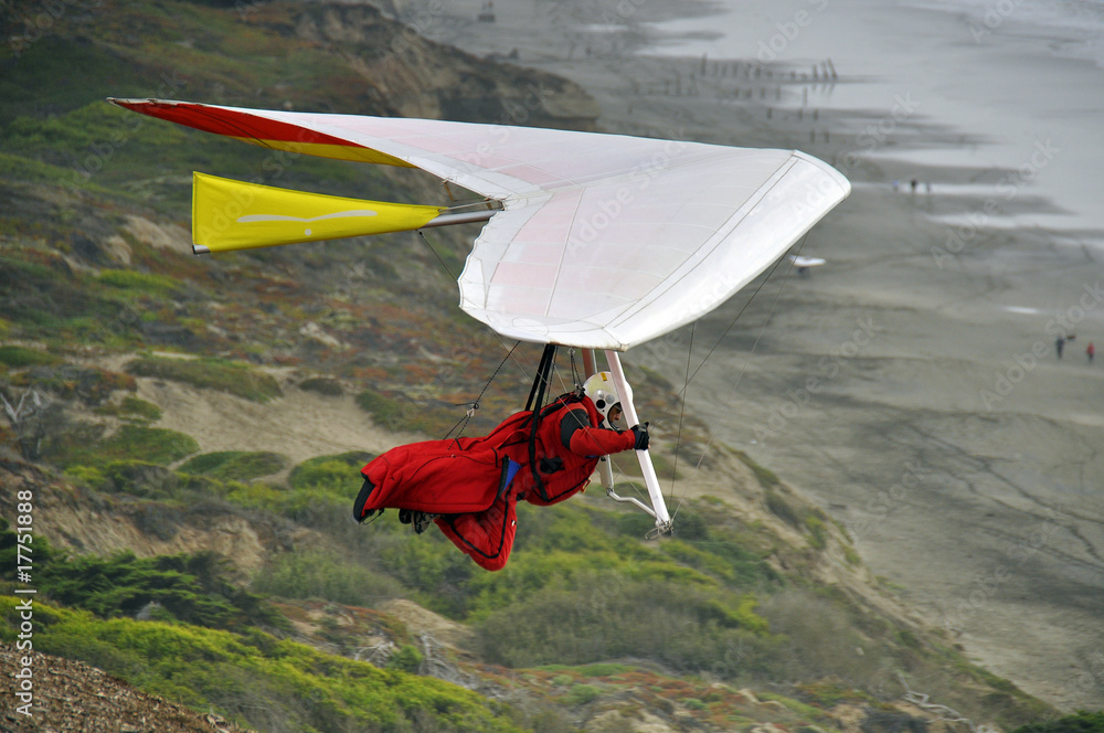 Wall mural photo of hand glider by seascape cliff