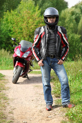 Fototapeta na wymiar motorcyclist standing on country road near bike