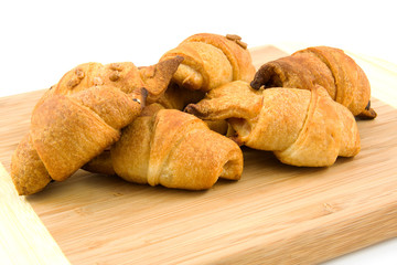 wooden board with home made croissants over white background