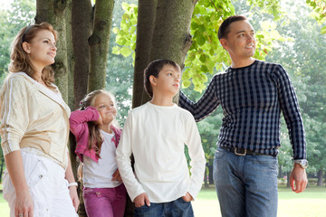 smiling happy family of four looking aside outdoors