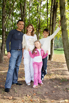 smiling happy family of four in park