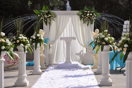 Outside wedding ceremony decoration,  luxury white decor with columns and flowers, wedding planner background