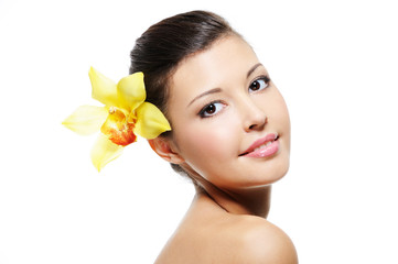 smiling female face with yellow orchid from her ear