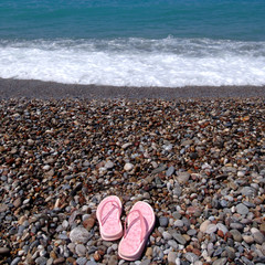 An image of flip-flops at the beach with pebble stones