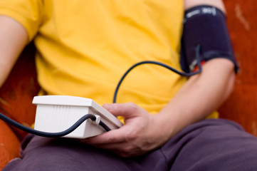 Man in yellow shirt is checking his blood pressure