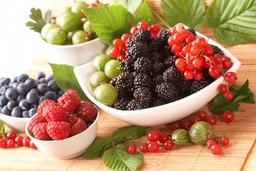 Berries in plates, on a table, among green leaves
