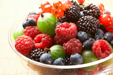 Fruit mix in the glass container, on a table from straw