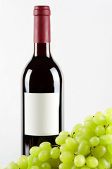 Obraz premium Bottle of red wine and green grapes in front