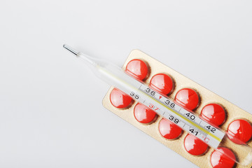 Glass thermometer on a pack of red pills with selective focus