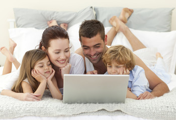 Family in bed using a laptop