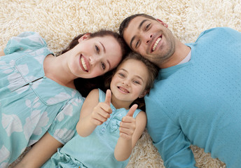 Parents and daughter on floor with thumbs up