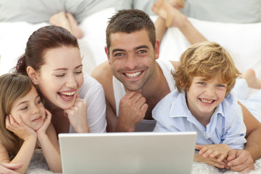 Family in bed having fun with a laptop
