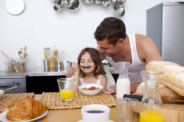 Obraz na płótnie Canvas Little girl enjoying her breakfast with her father