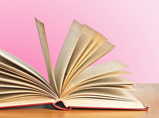Open book on desk  on pink background
