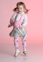 Little girl is playing with rabbit toy in studio