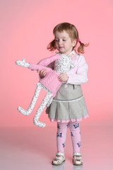 Little girl is playing with rabbit toy in studio