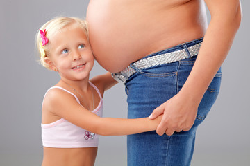 little girl hearing on mothers tummy