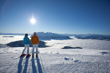 couple on skies looking at mountains appearing out of fog