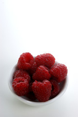 some organice raspberries in a white bowl