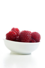 some organice raspberries in a white bowl