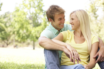 Fototapeta premium Portrait Of Young Couple Sitting In Park