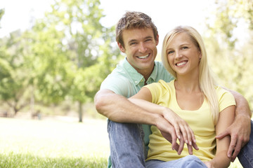 Fototapeta premium Portrait Of Young Couple Sitting In Park