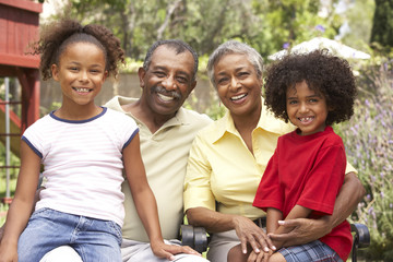 Grandparents Relaxing In Garden With Grandchildren
