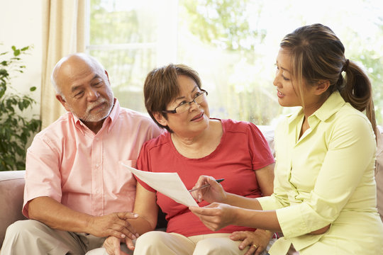 Senior Couple Talking To Financial Advisor At Home