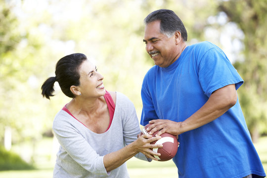 Senior Couple Exercising With American Football In Park