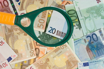 Magnifying glass and a bunch of euro bills